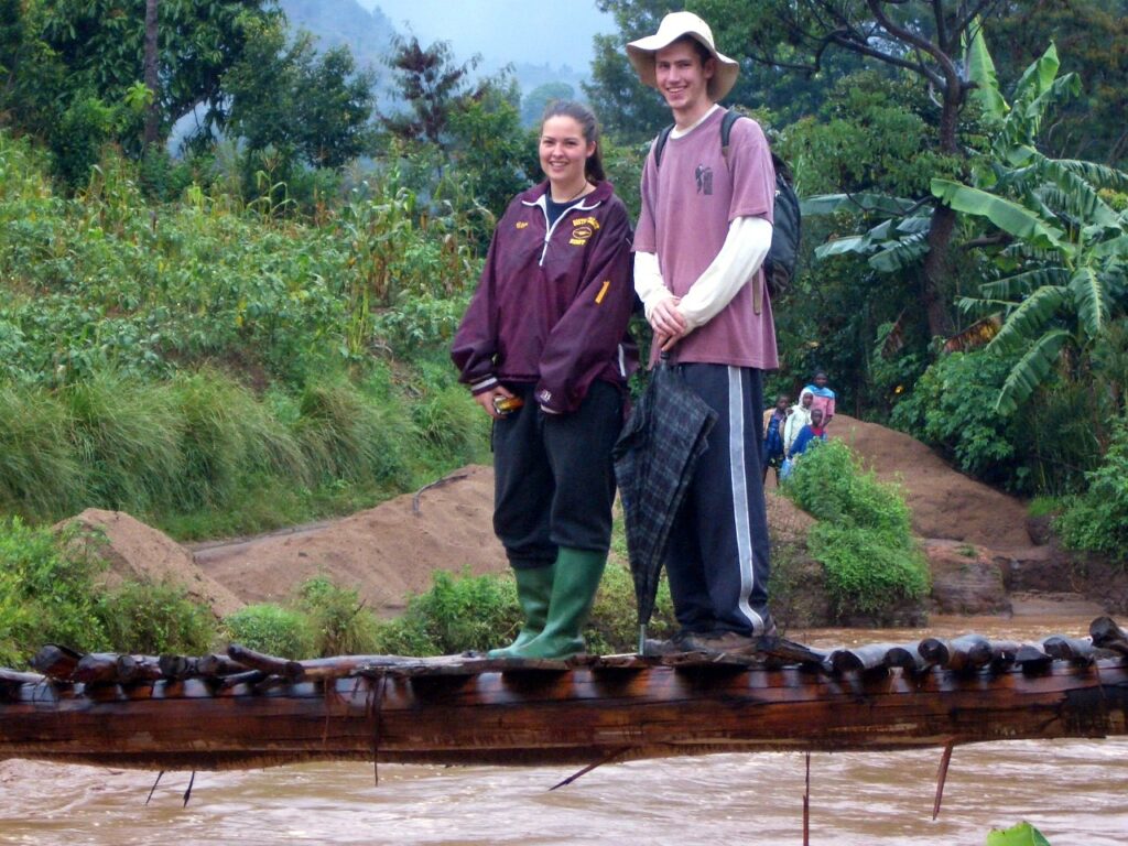 Clare and Neil on a log walking bridge over a river in Tanzania