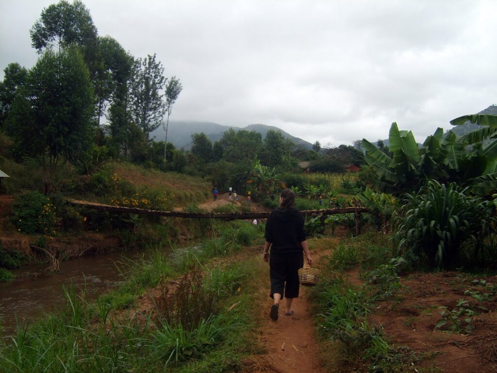 Clare walking on a path through mountain farms in Tanzania